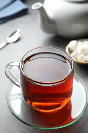 Photo of Refreshing black tea in cup on grey table, closeup