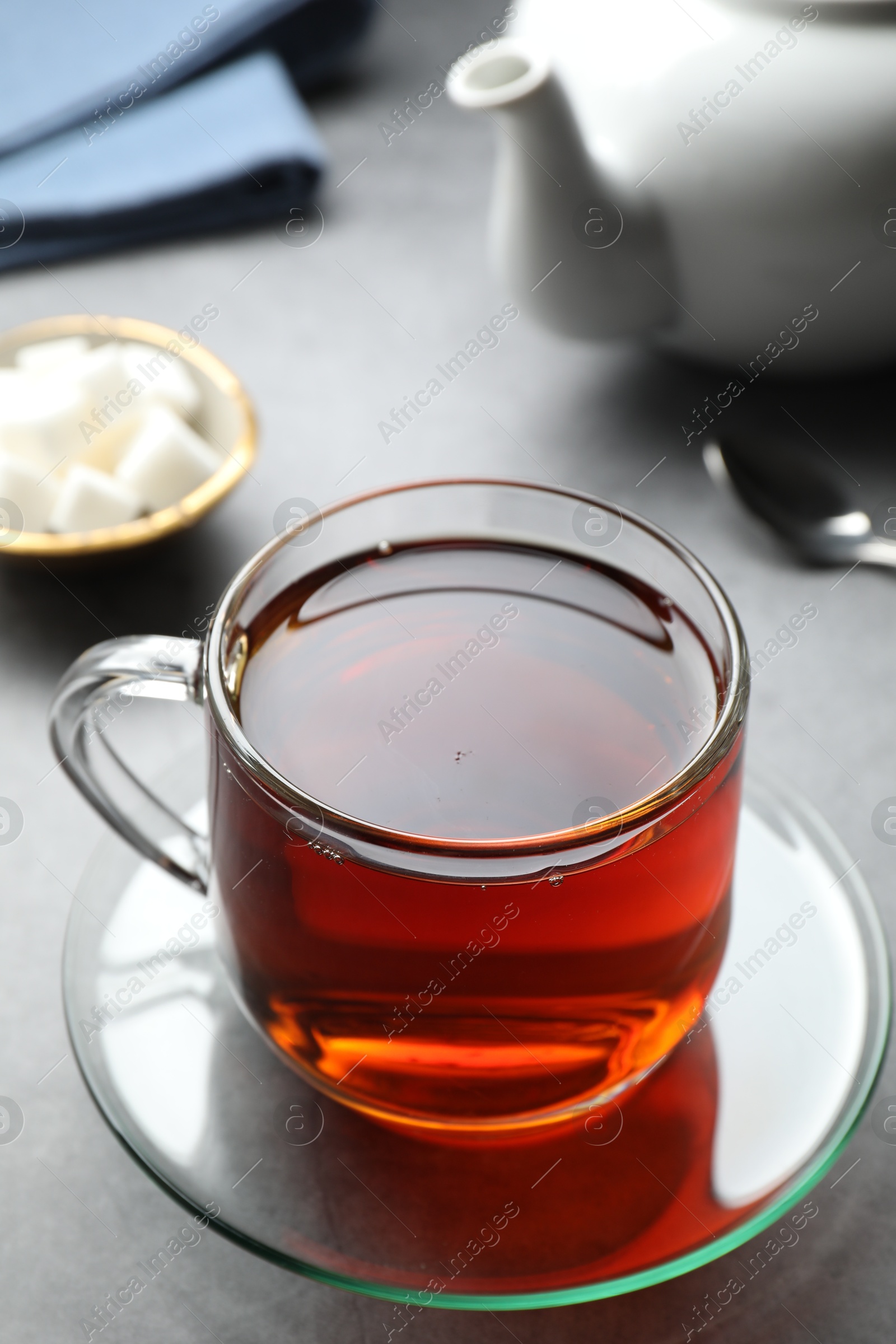 Photo of Refreshing black tea in cup on grey table, closeup