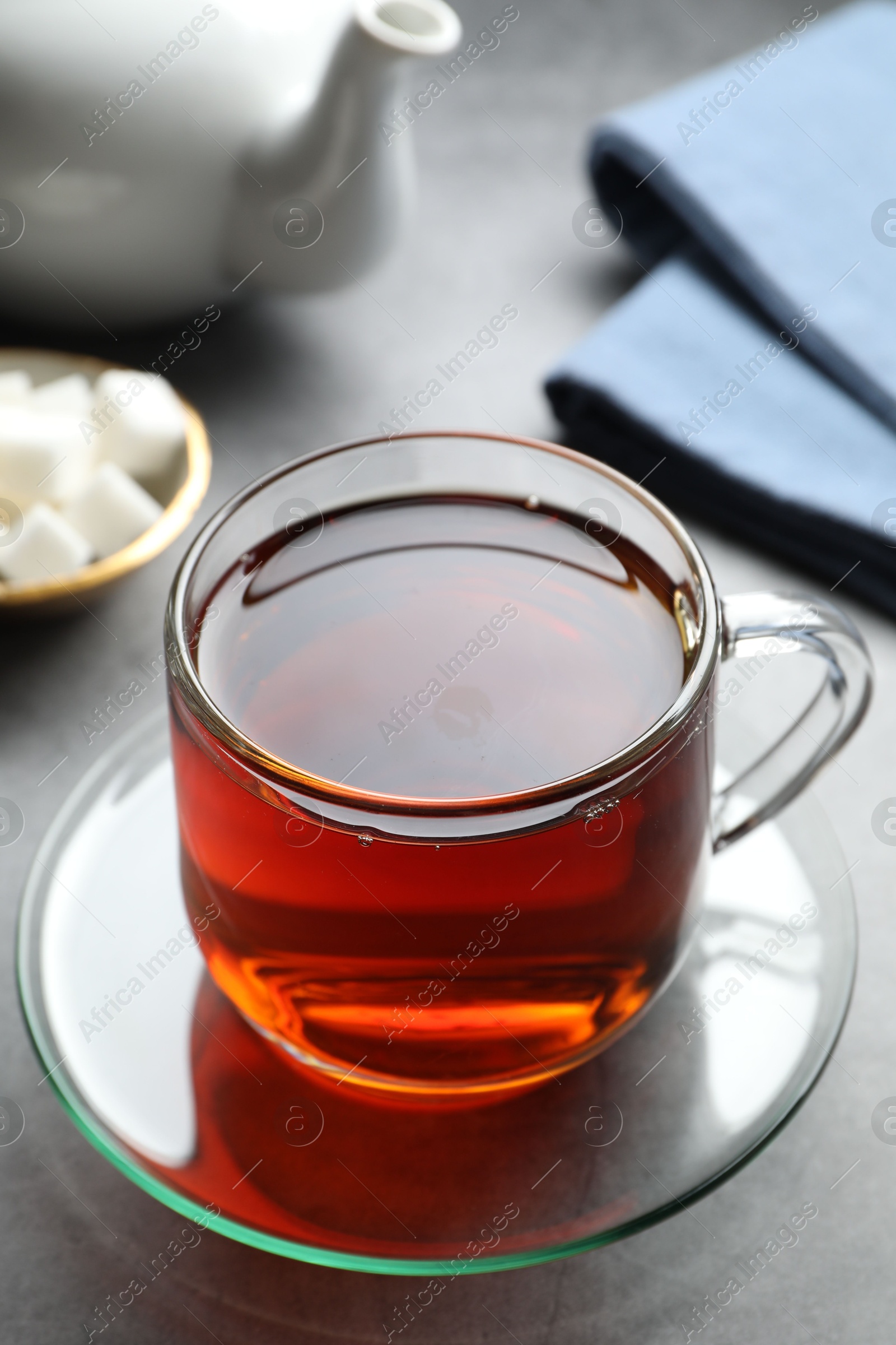 Photo of Refreshing black tea in cup on grey table, closeup