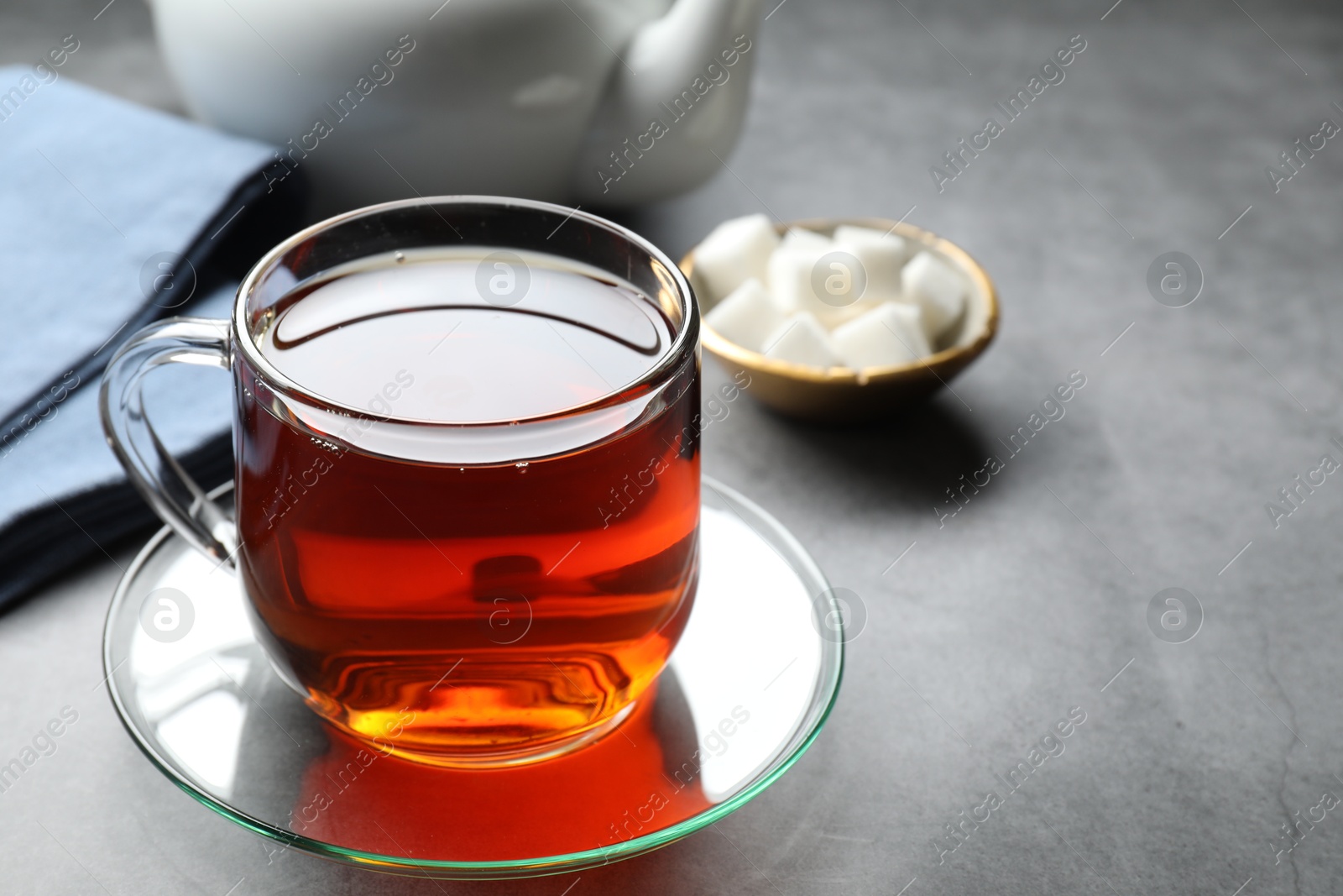 Photo of Refreshing black tea in cup on grey table, closeup. Space for text