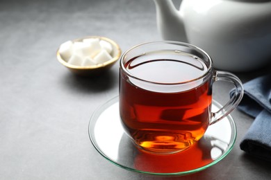 Photo of Refreshing black tea in cup on grey table, closeup. Space for text