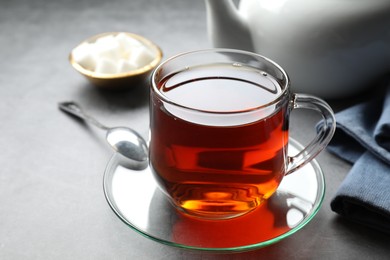 Photo of Refreshing black tea in cup on grey table, closeup