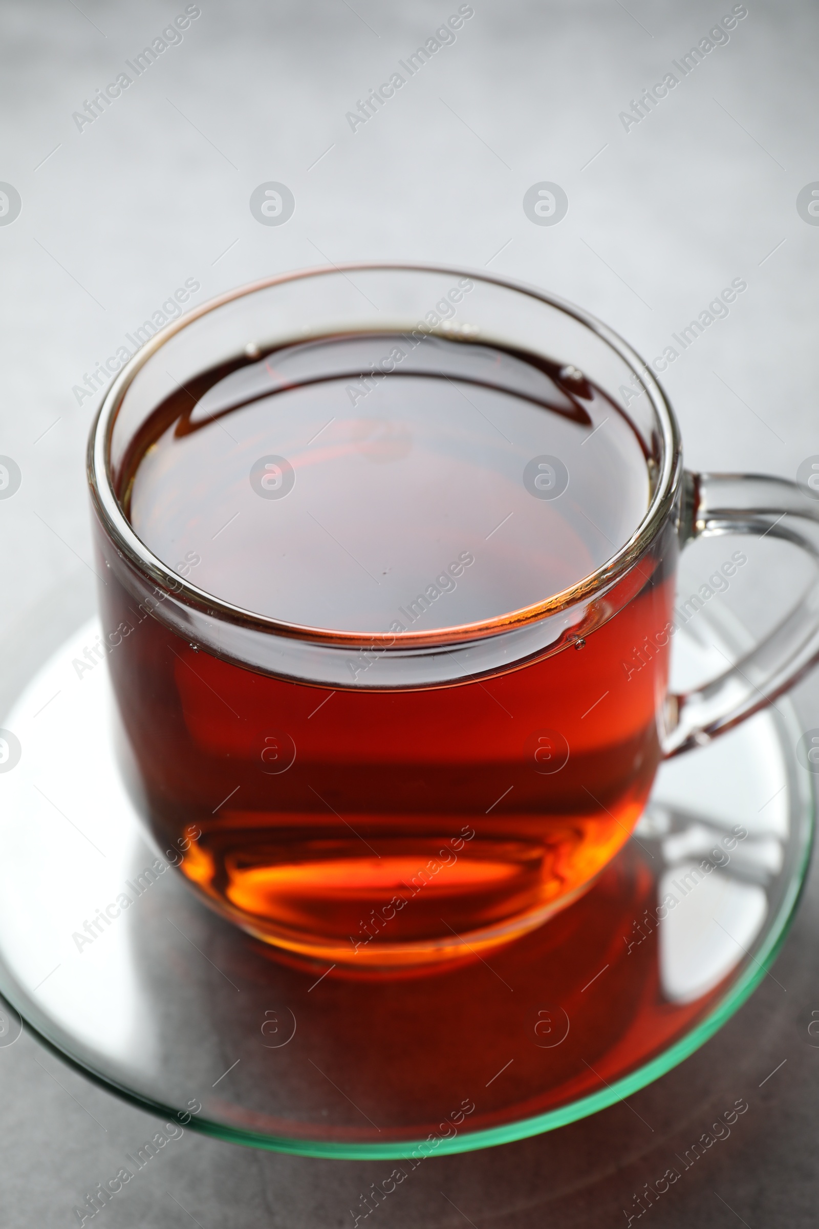 Photo of Refreshing black tea in cup on grey table, closeup