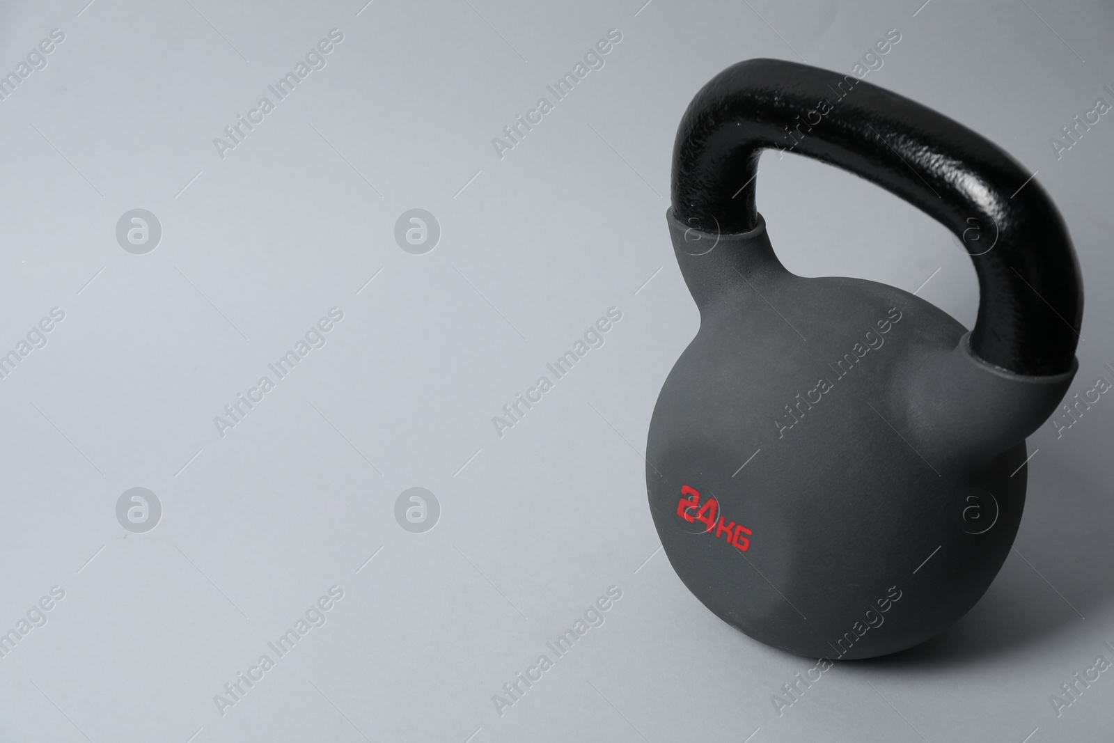 Photo of One metal kettlebell on grey background, space for text. Sports equipment