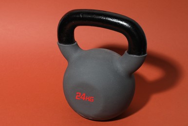 Photo of One metal kettlebell on coral background. Sports equipment