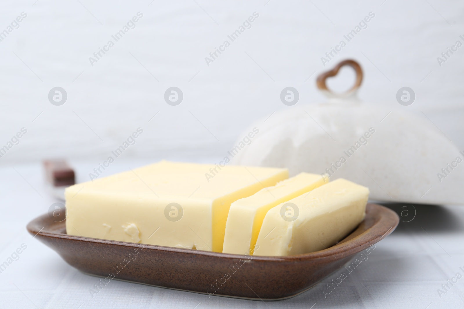 Photo of Cut tasty butter in dish on white table, closeup