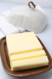 Photo of Cut tasty butter in dish on table, closeup