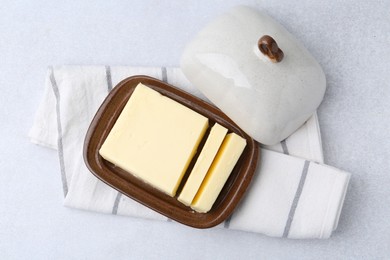 Photo of Cut tasty butter in dish on light grey table, top view