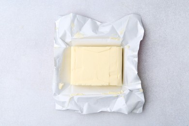 Photo of Block of tasty butter in open package on light grey table, top view