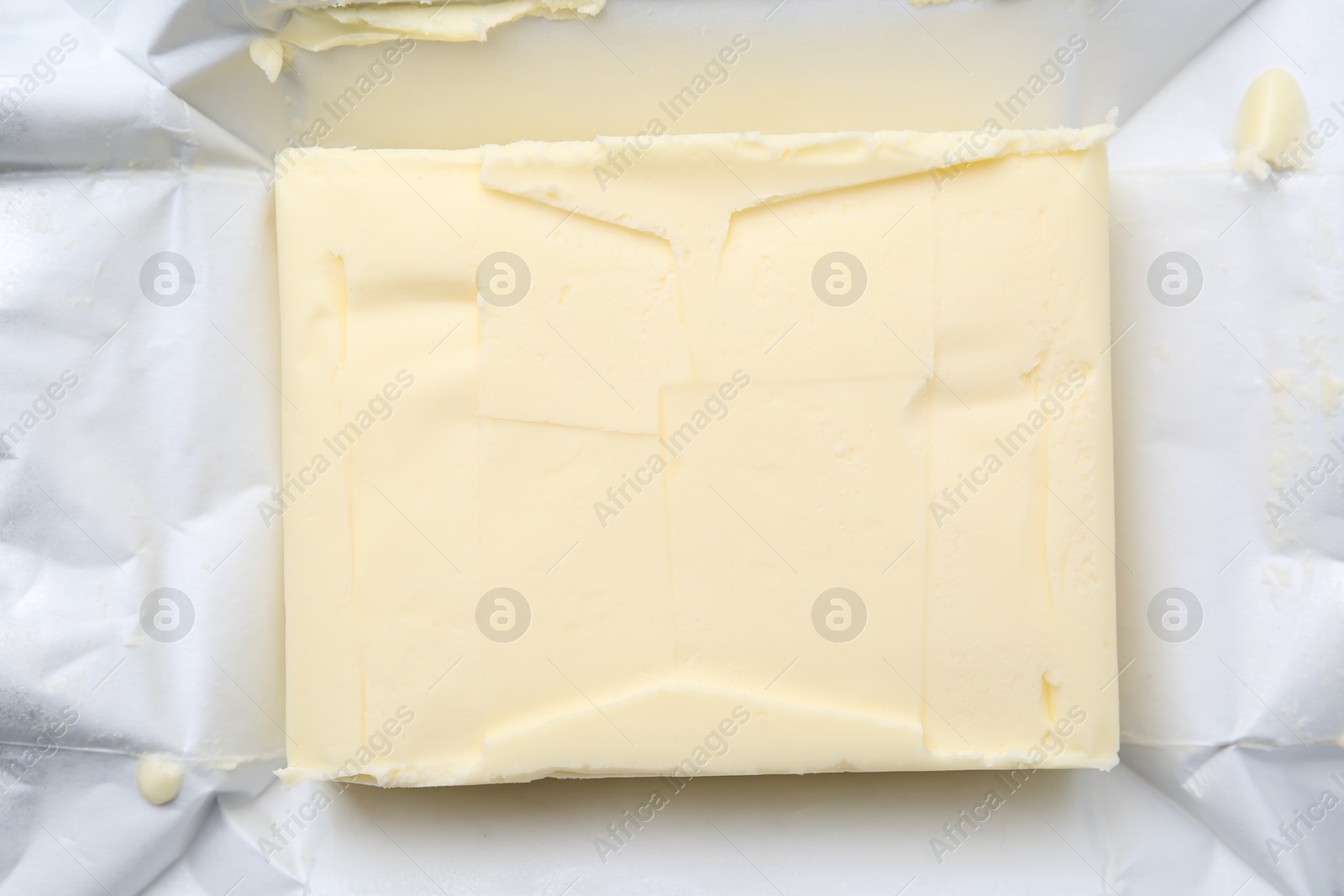 Photo of Block of tasty butter in open package, top view