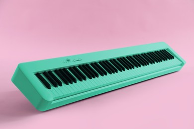 Image of Cyan color synthesizer on pink background. Electronic musical instrument