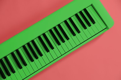 Image of Green synthesizer on pink background, top view. Electronic musical instrument