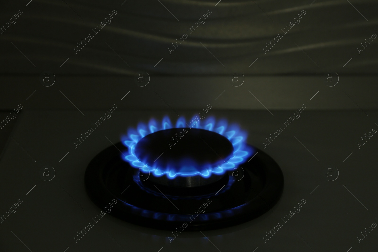 Photo of Gas burner of modern stove with burning blue flame at night