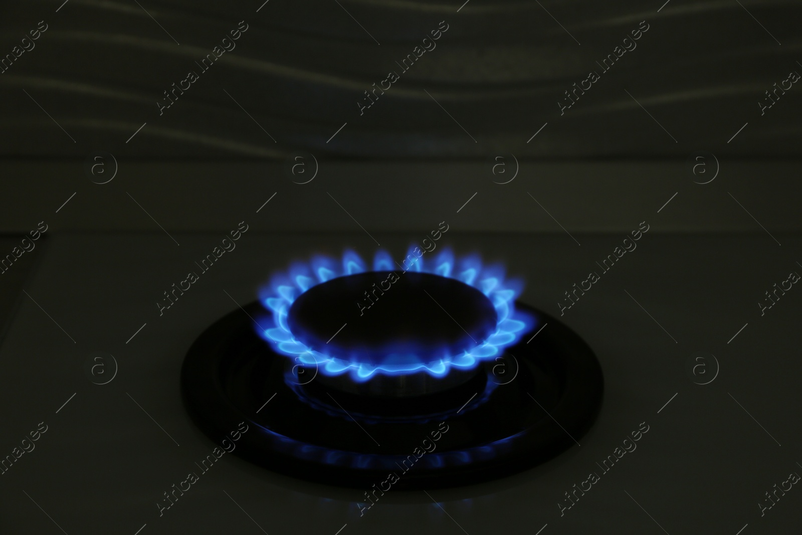 Photo of Gas burner of modern stove with burning blue flame at night