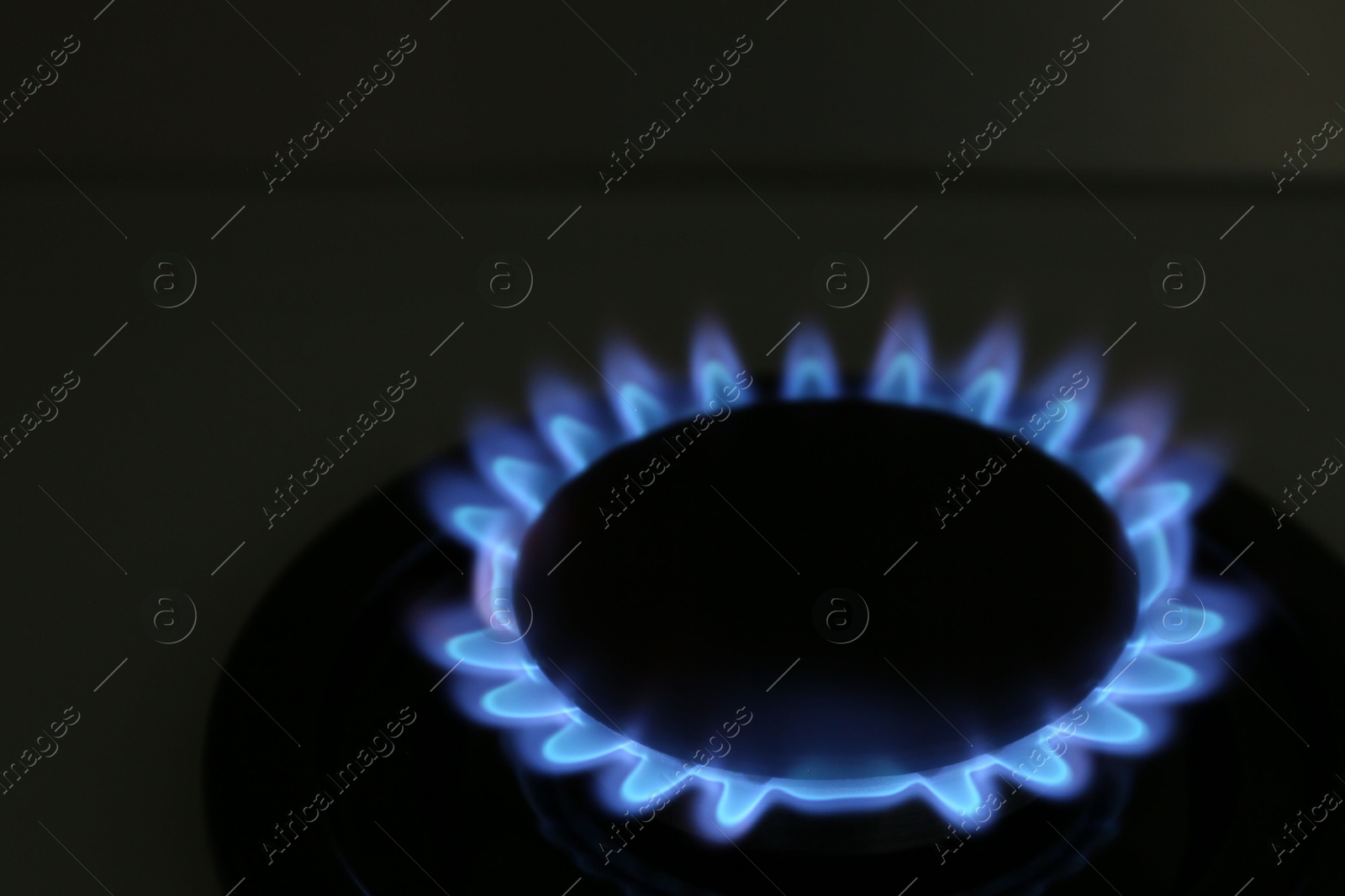 Photo of Gas burner of modern stove with burning blue flame at night