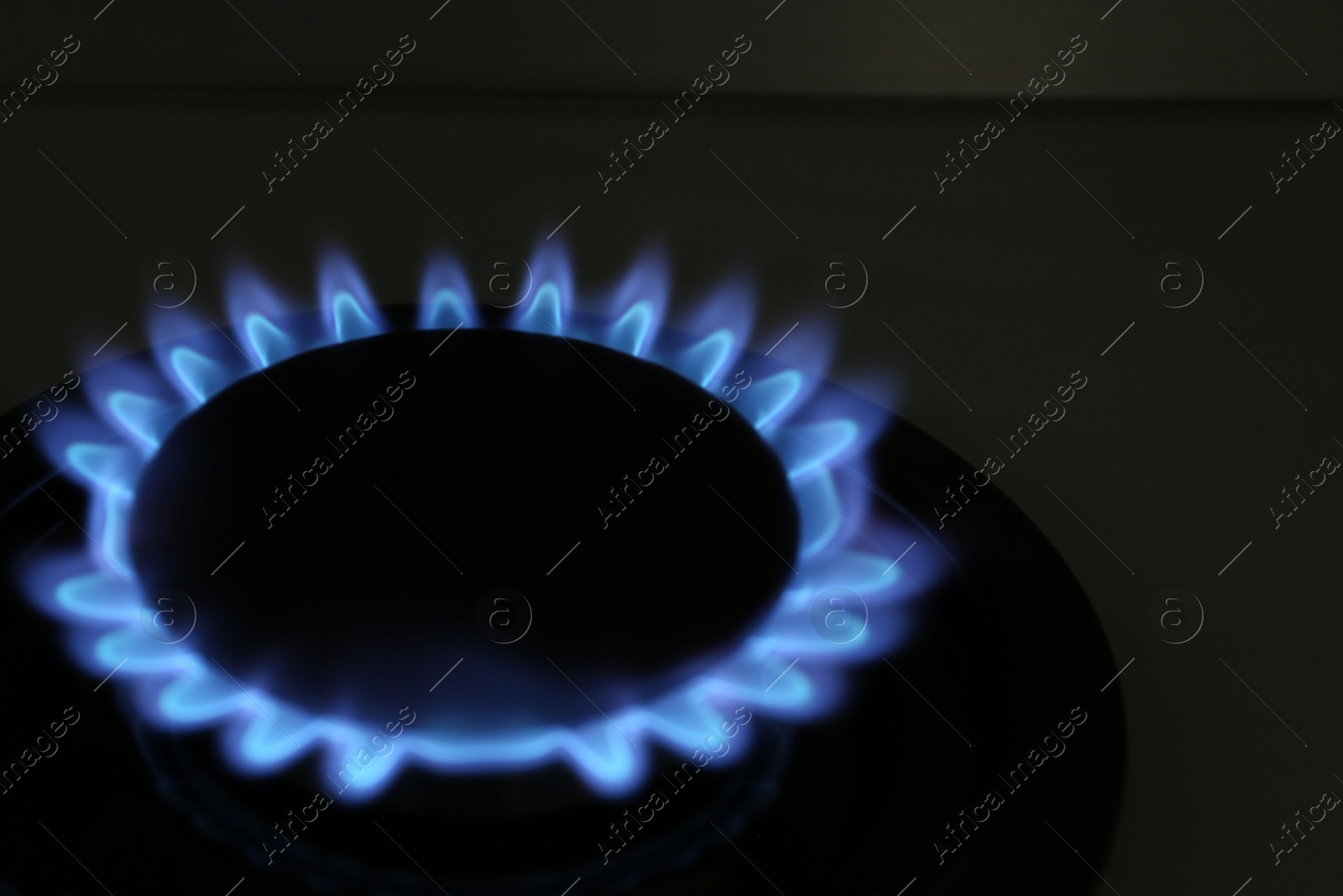 Photo of Gas burner of modern stove with burning blue flame at night