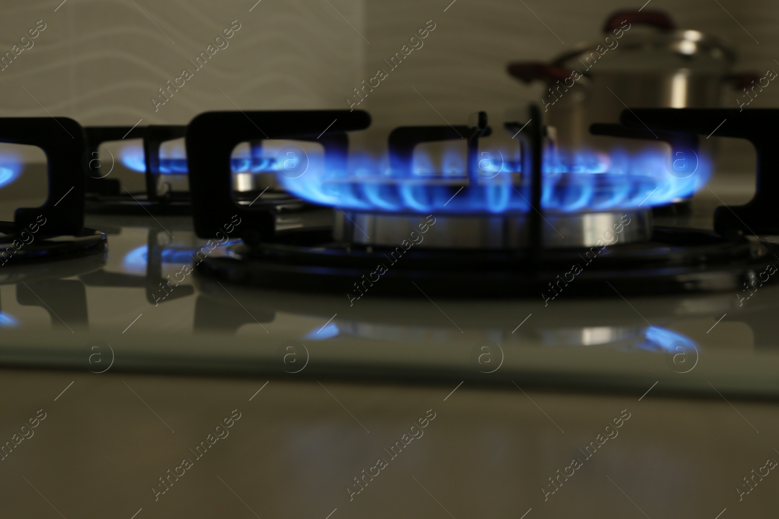 Photo of Modern gas cooktop with burning blue flames in kitchen