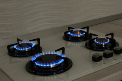 Photo of Modern gas cooktop with burning blue flames in kitchen