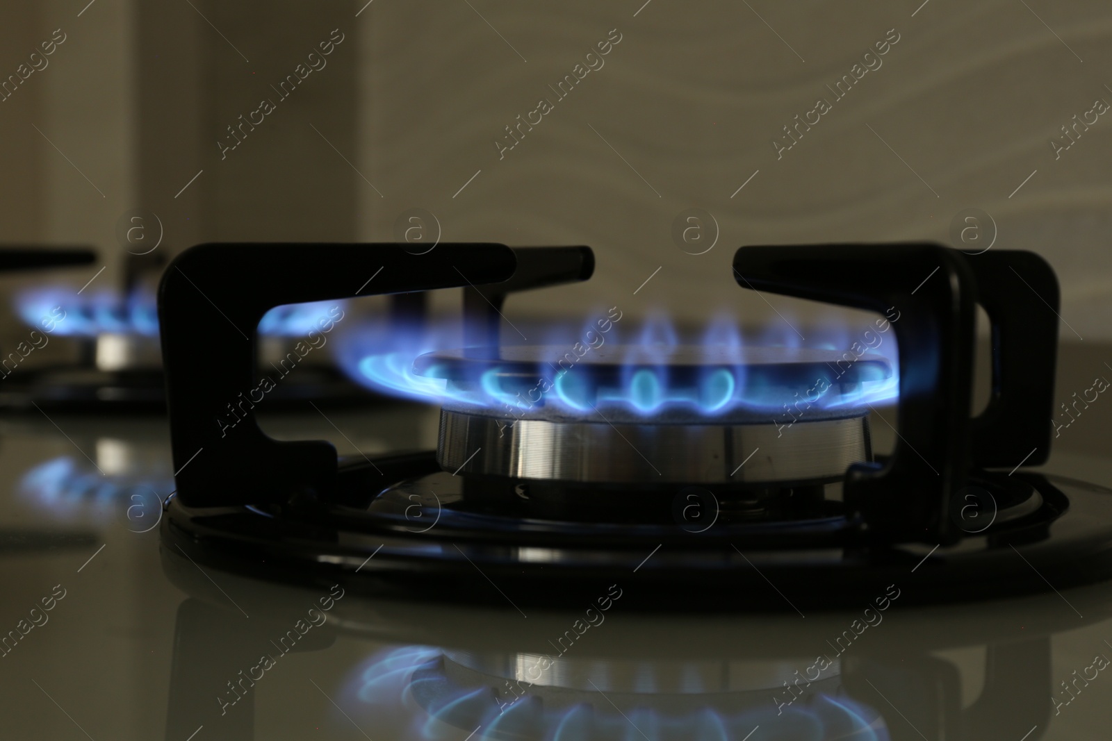 Photo of Gas burner of modern stove with burning blue flame, closeup