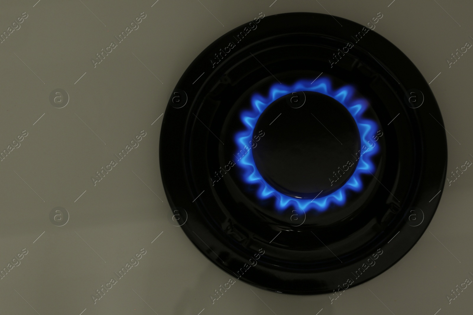 Photo of Gas burner of modern stove with burning blue flame, top view