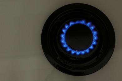 Photo of Gas burner of modern stove with burning blue flame, top view