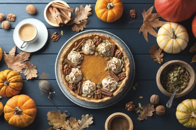 Flat lay composition with homemade pumpkin pie with whipped cream, seeds and cinnamon on blue wooden table