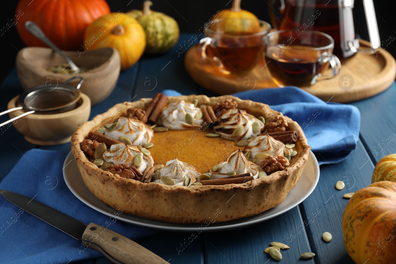 Photo of Homemade pumpkin pie with whipped cream, seeds and cinnamon on blue wooden table