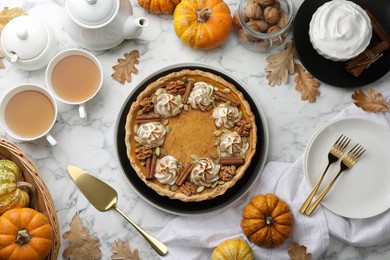 Flat lay composition with homemade pumpkin pie with whipped cream, seeds and cinnamon on white marble table