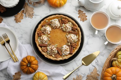 Photo of Flat lay composition with homemade pumpkin pie with whipped cream, seeds and cinnamon on white marble table