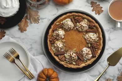 Flat lay composition with homemade pumpkin pie with whipped cream, seeds and cinnamon on white marble table