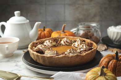 Photo of Homemade pumpkin pie with whipped cream, seeds and cinnamon on white marble table