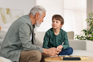 Grandpa and his grandson playing dominoes at table indoors