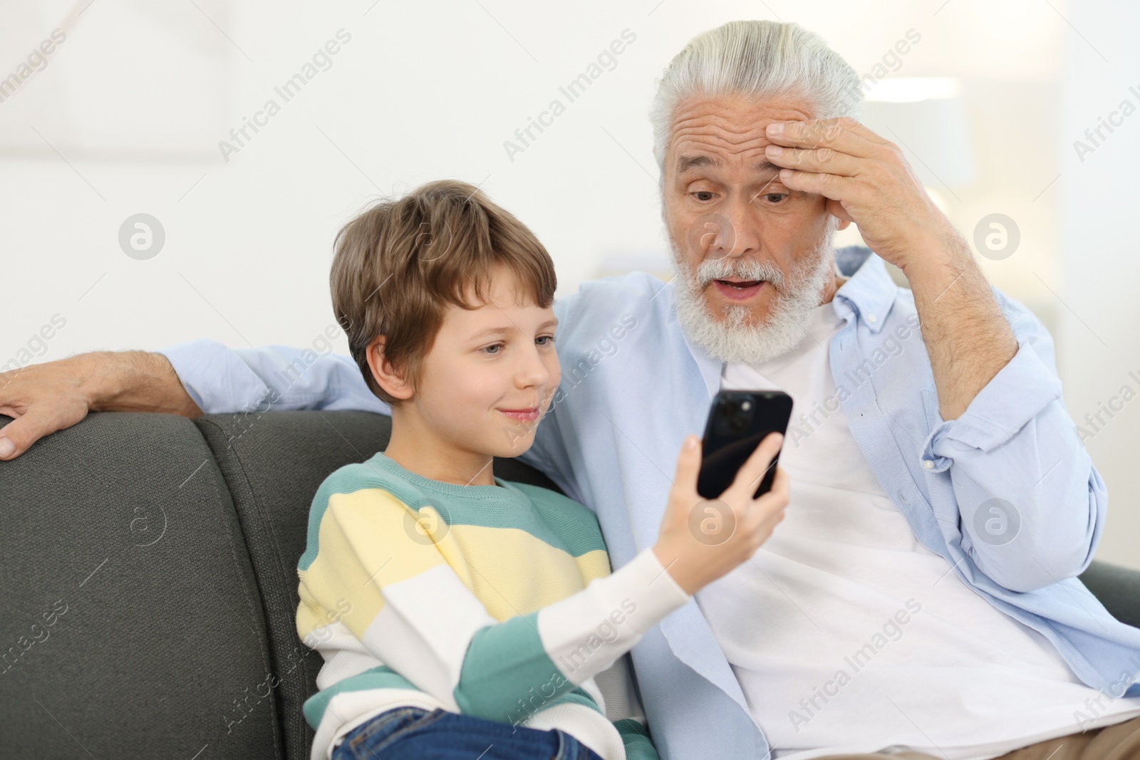 Photo of Grandpa and his grandson watching something on smartphone at home