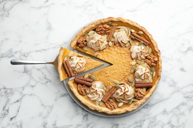 Photo of Tasty homemade pumpkin pie with server on white marble table, top view