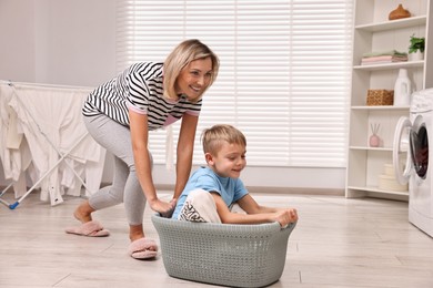 Photo of Happy housewife and her son playing together in laundry room