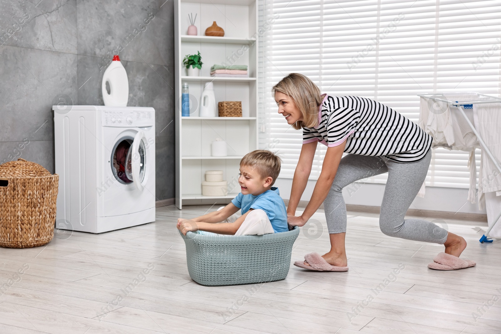 Photo of Happy housewife and her son playing together in laundry room