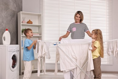 Photo of Happy housewife and her kids doing laundry together at home