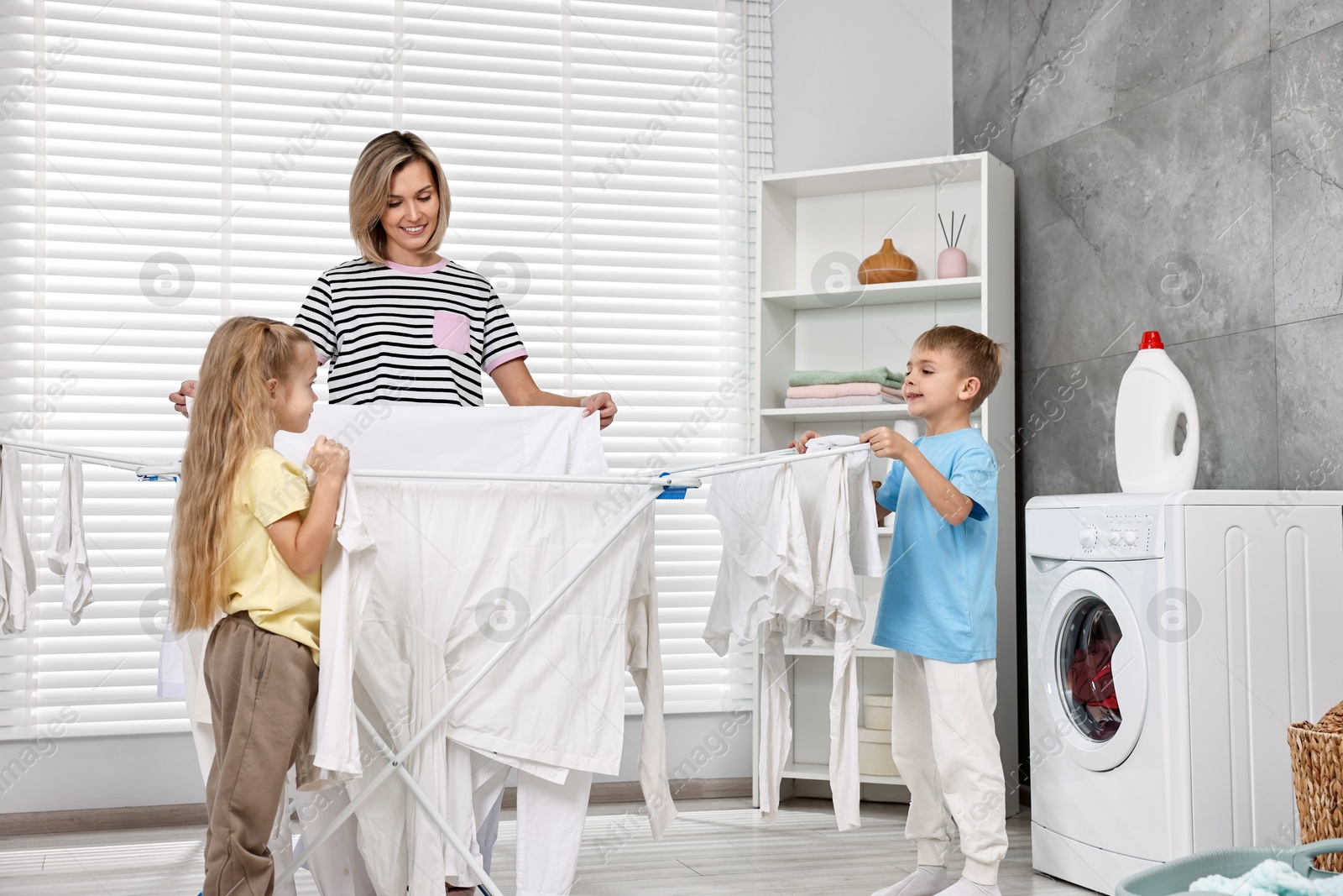 Photo of Happy housewife and her kids doing laundry together at home