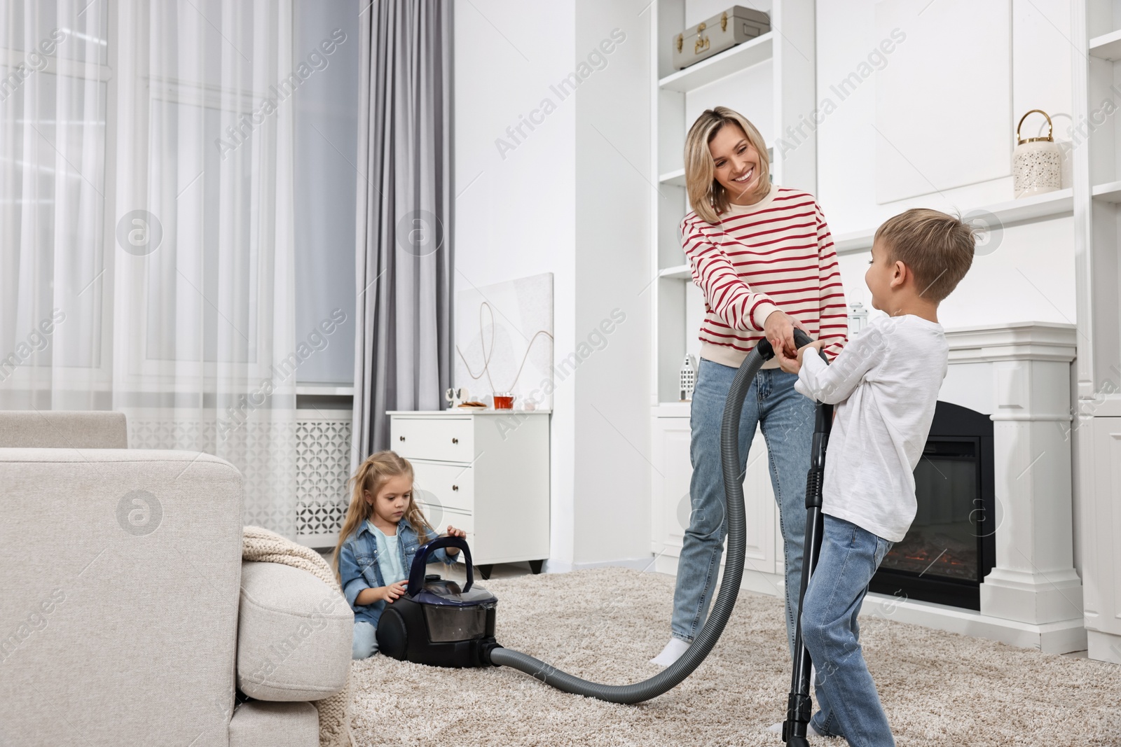 Photo of Housewife and her kids having fun while vacuuming floor together