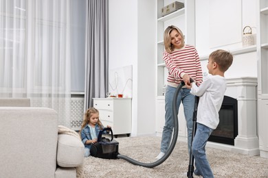 Housewife and her kids having fun while vacuuming floor together