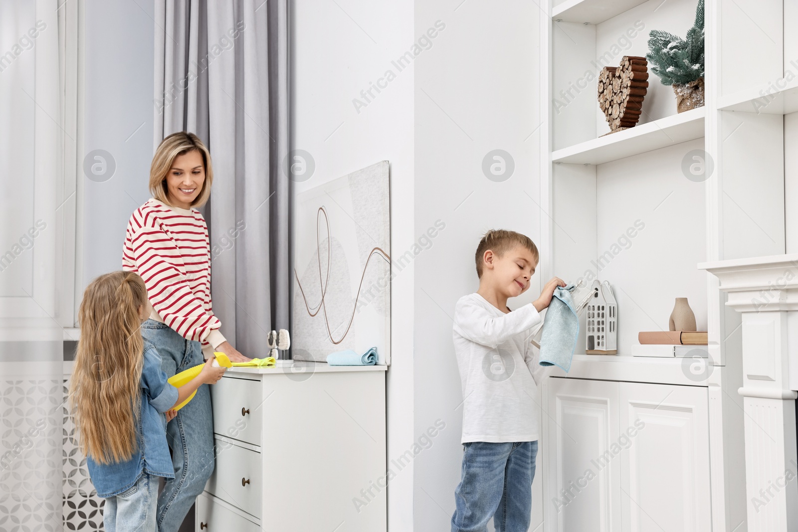 Photo of Happy housewife and her kids cleaning room together