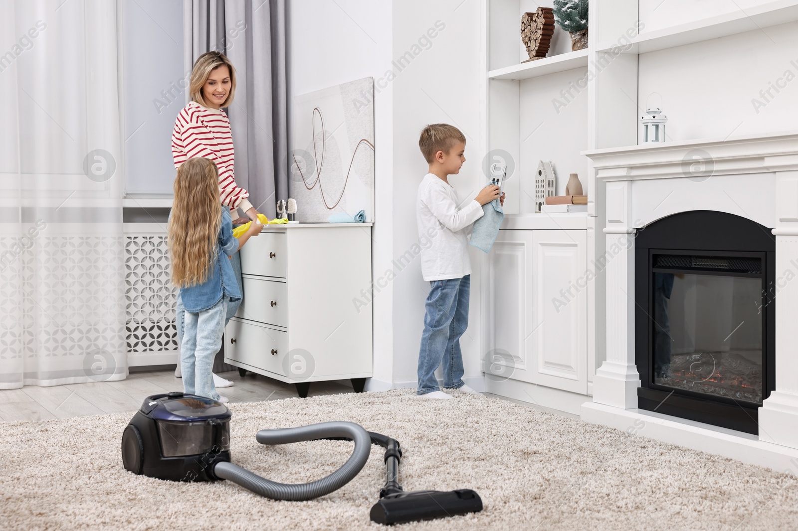 Photo of Happy housewife and her kids cleaning room together