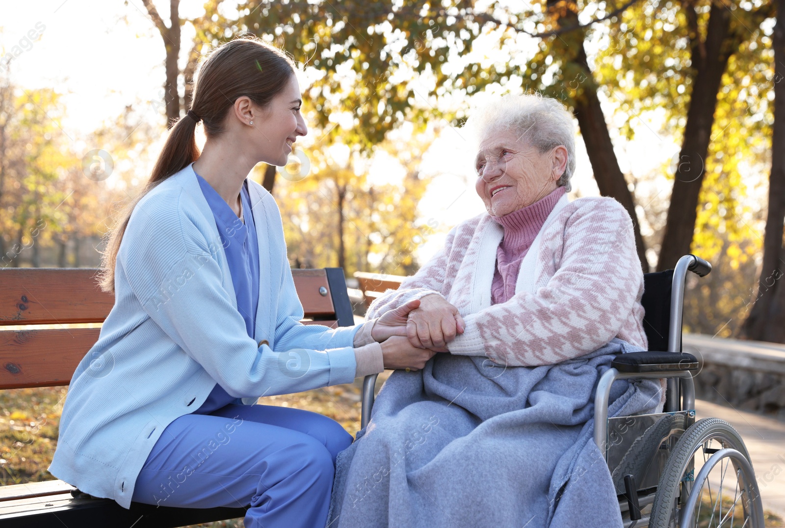 Photo of Caregiver with elderly woman in wheelchair at park