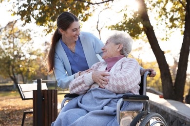 Caregiver with elderly woman in wheelchair at park