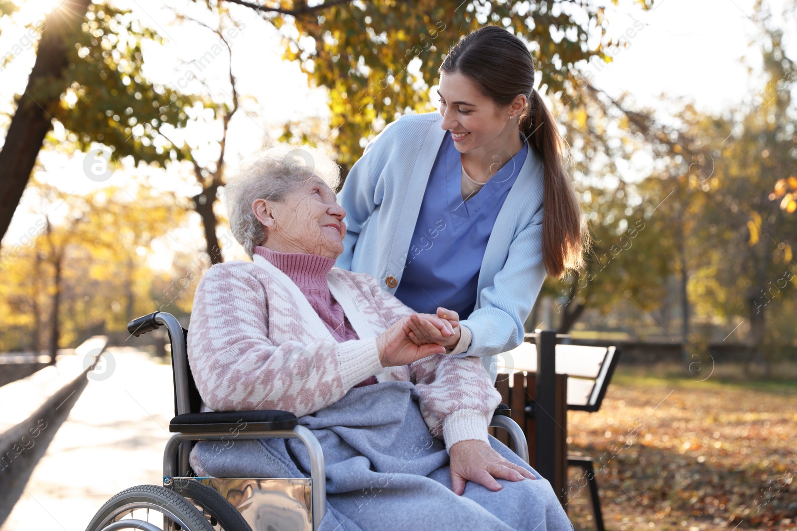 Photo of Caregiver with elderly woman in wheelchair at park