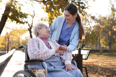 Photo of Caregiver with elderly woman in wheelchair at park