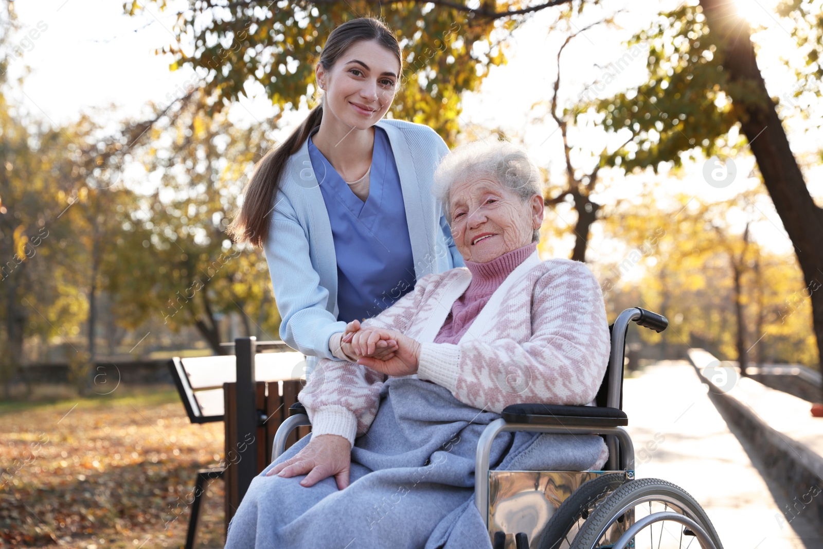 Photo of Caregiver with elderly woman in wheelchair at park