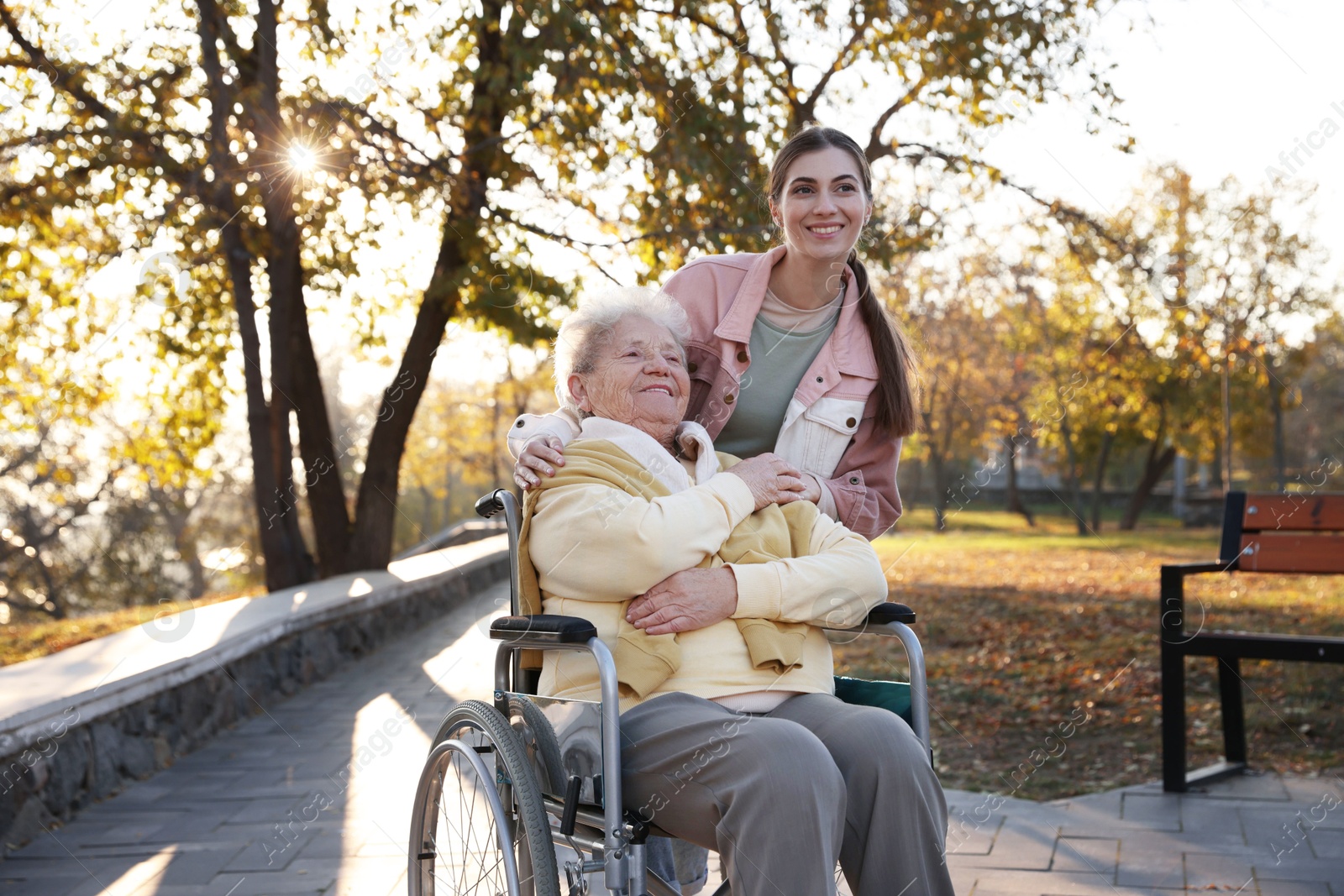 Photo of Caregiver with elderly woman in wheelchair at park