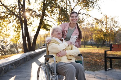 Caregiver with elderly woman in wheelchair at park