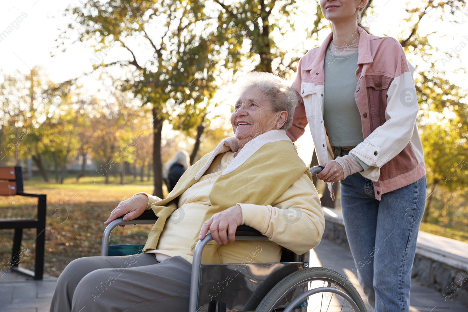 Photo of Caregiver with elderly woman in wheelchair at park